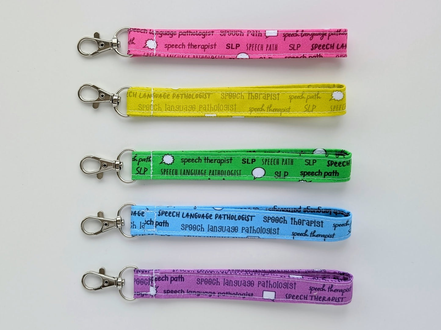 Five colorful keychains with text on a white background