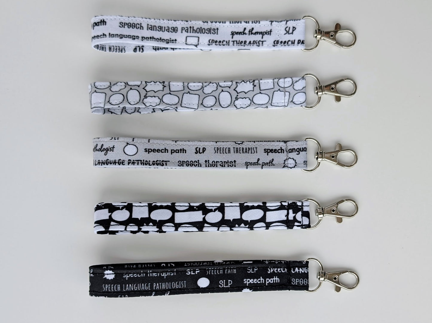 Set of five grayscale lanyards with 'speech language pathologist' text on a white background