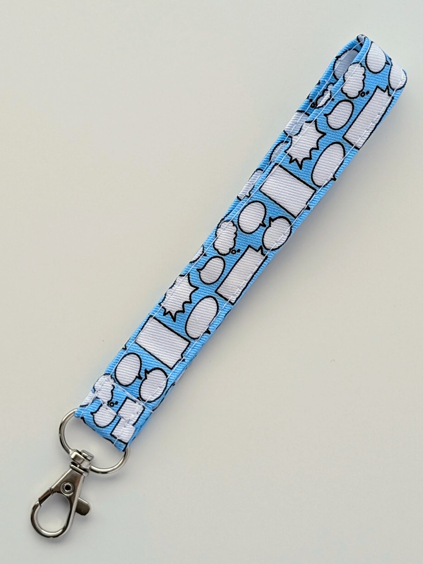 Blue lanyard with white speech bubble pattern on a light gray background