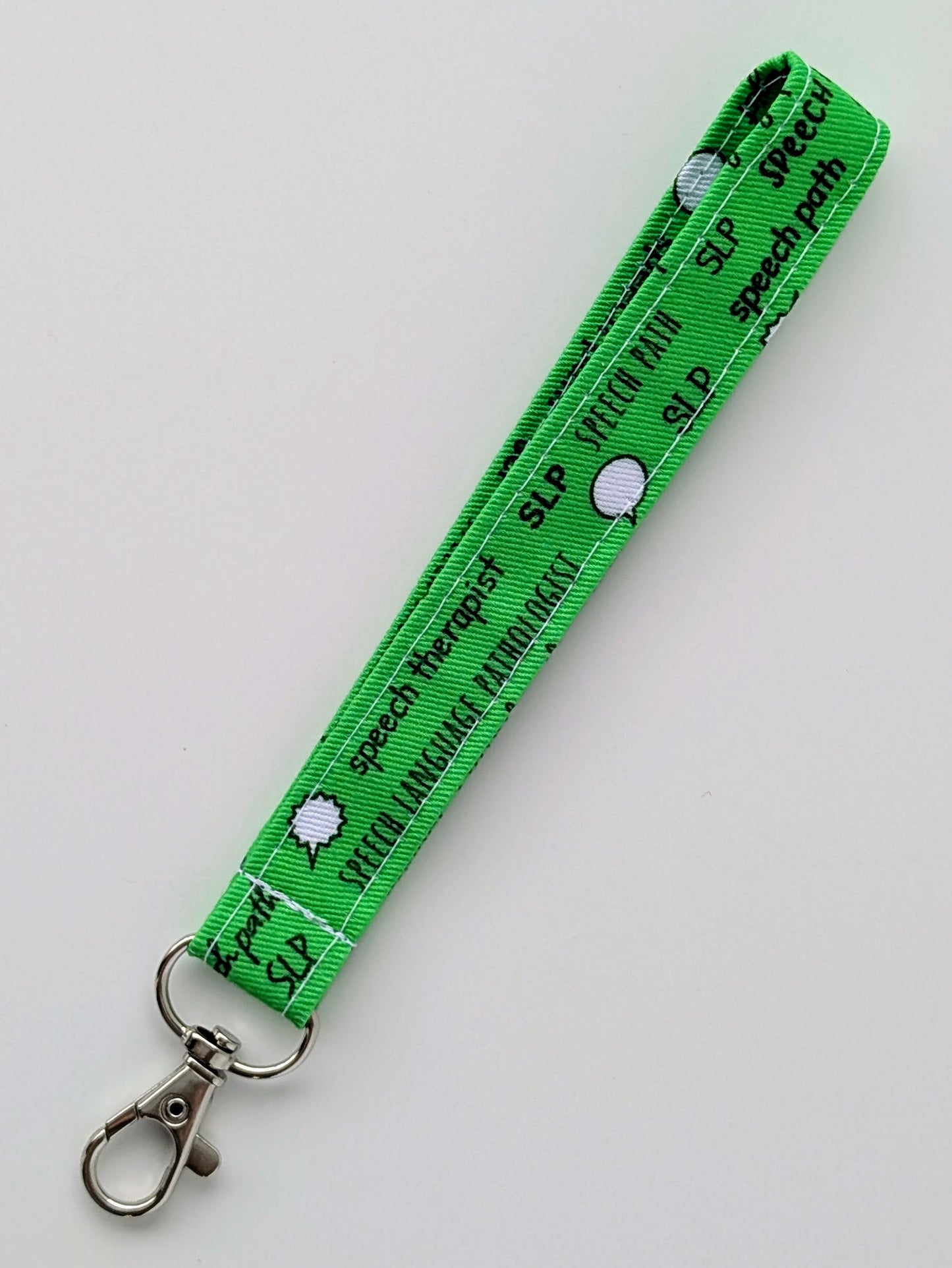 Green lanyard with text and a key ring on a light gray background
