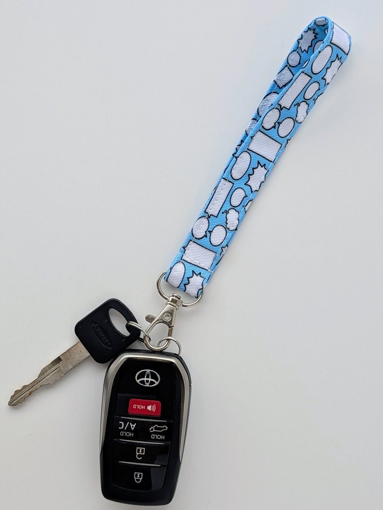 Car key fob with a blue lanyard featuring speech bubbles on a light gray background