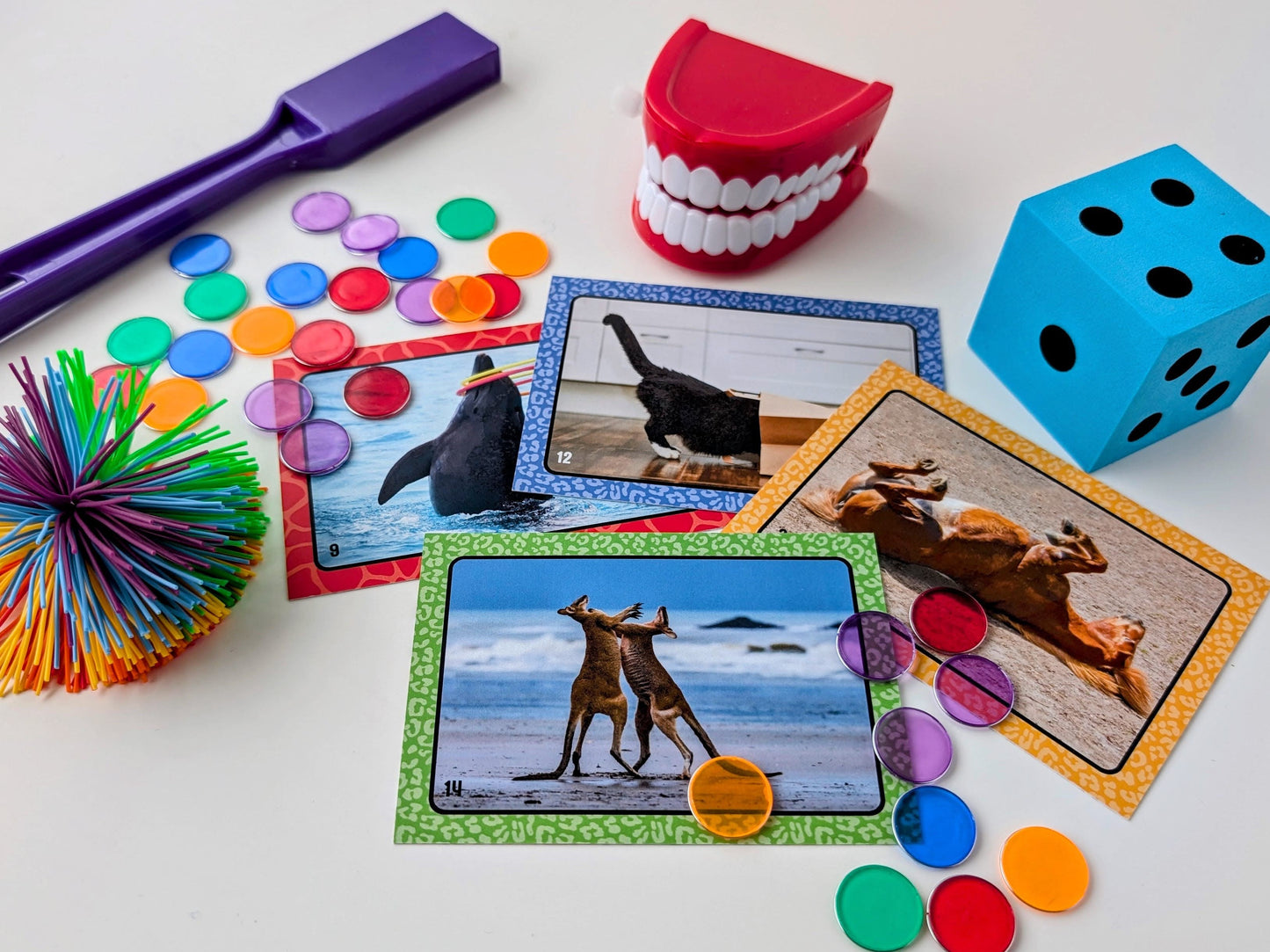 Educational game with cards, dice, and colorful objects on a white surface