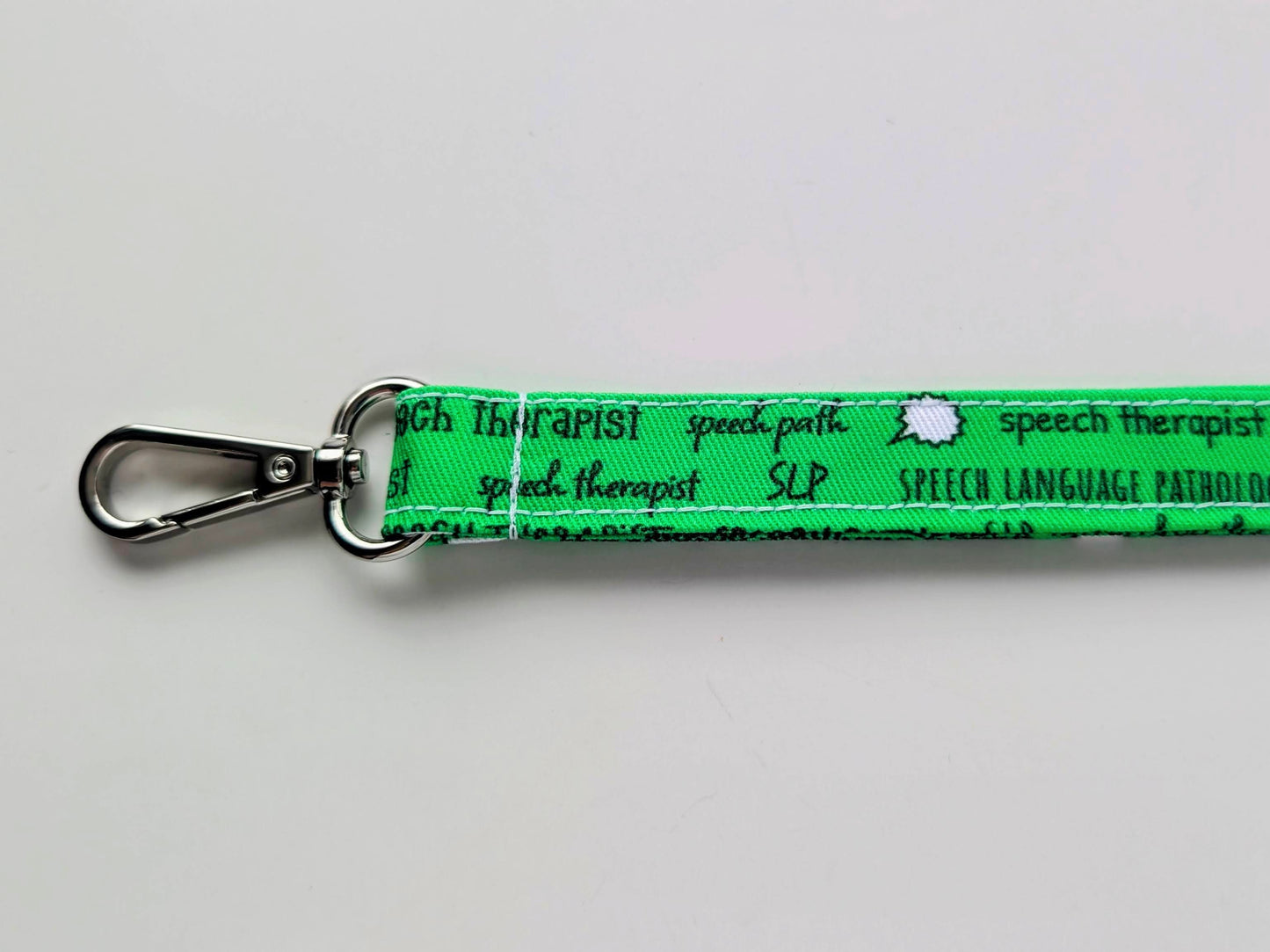 Green keychain with 'speech therapist' text on a white background