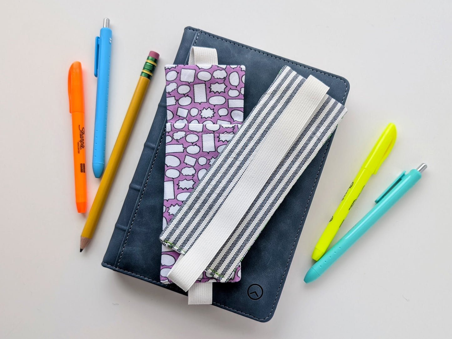 Notebook with colorful pens and pencils on a white background