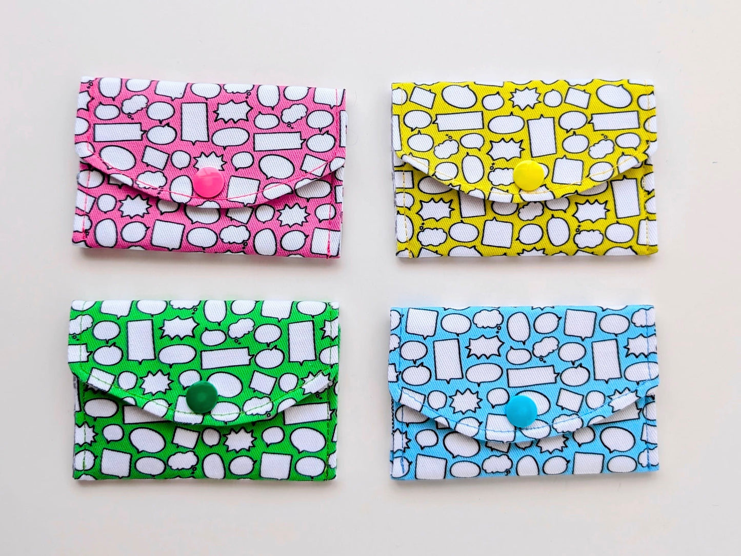 Four colorful patterned pouches with buttons on a light background