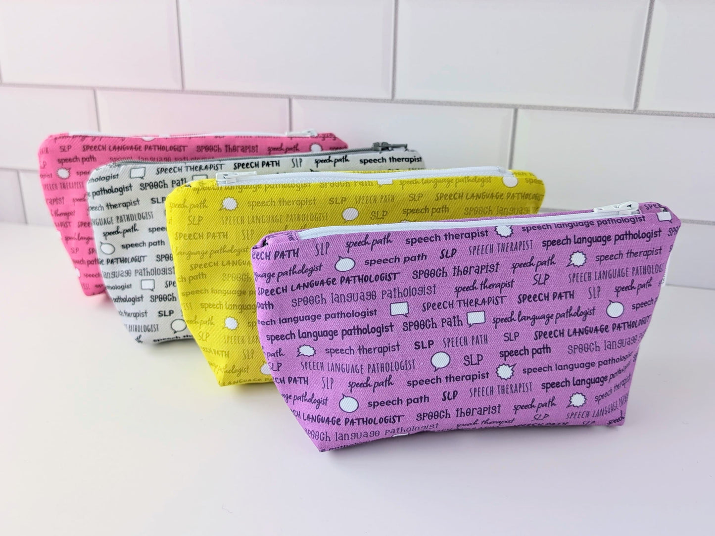 Four pouches with text patterns on a white surface and tiled wall background