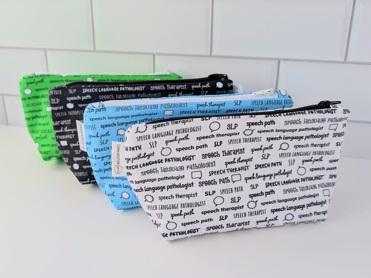 Four pouches with text design on a white surface and tiled wall background
