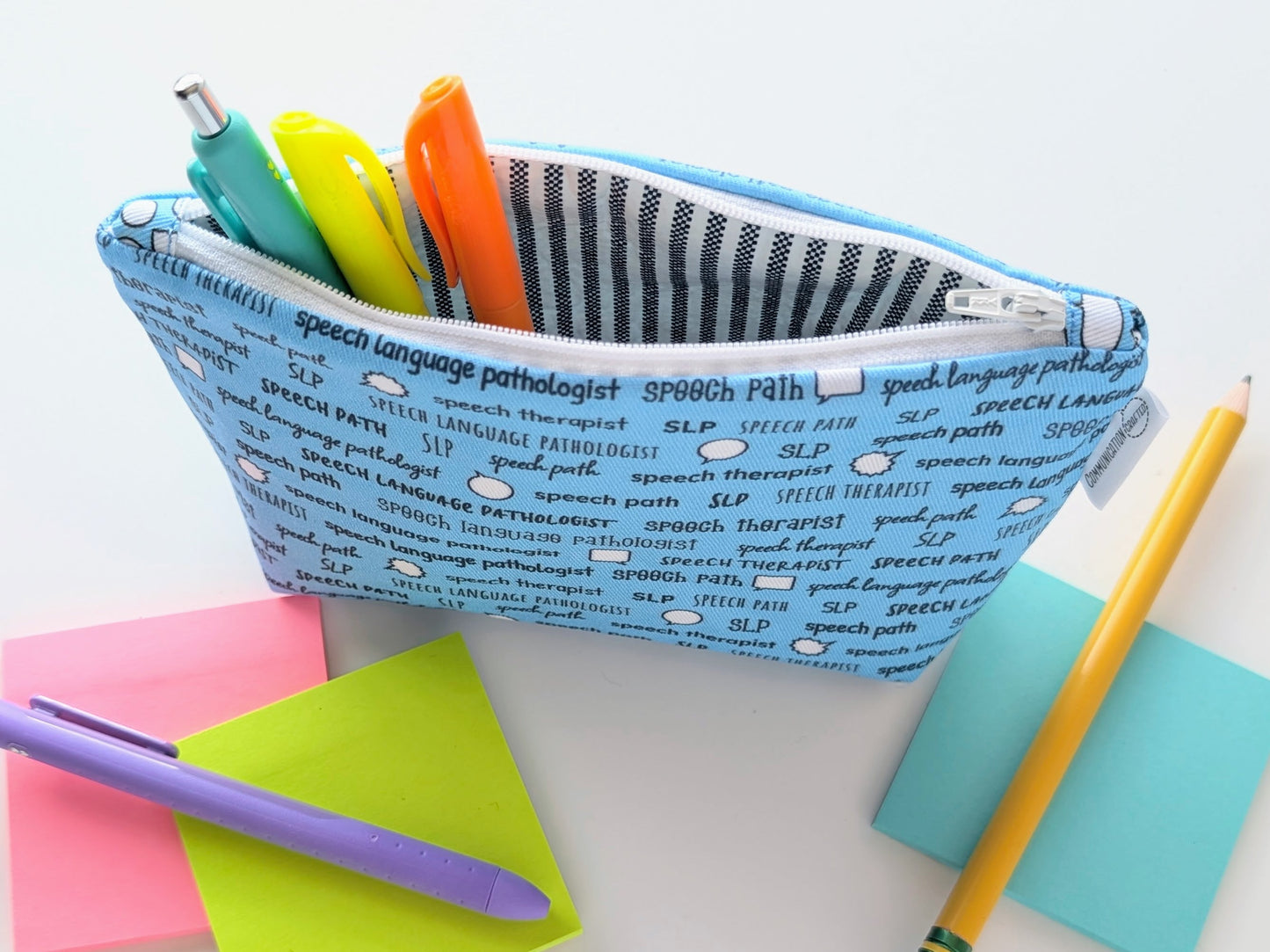 Pencil case with colorful pens and a pencil on a light background