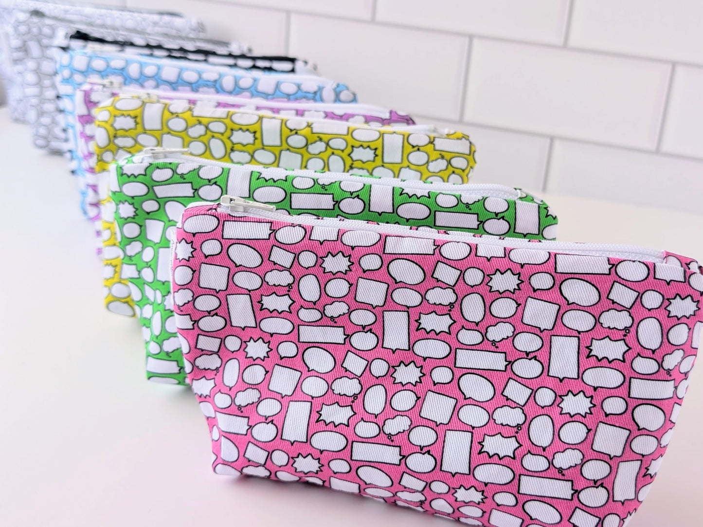 Set of colorful patterned pouches on a white surface with tiled background