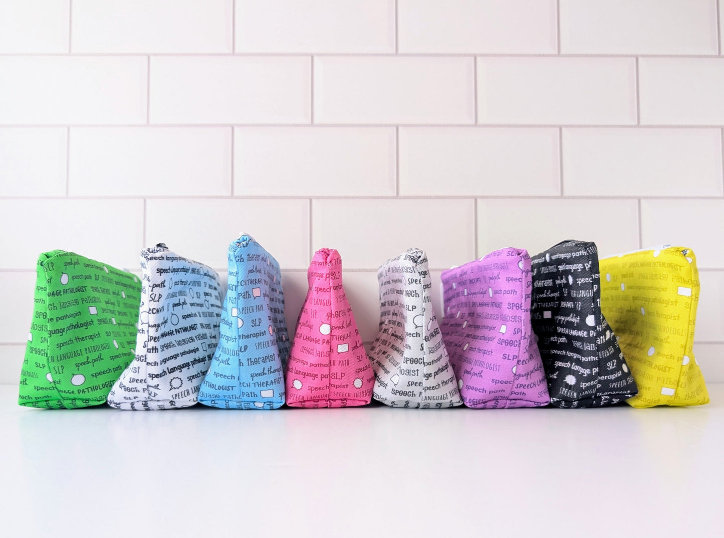 Colorful fabric bags with text on a white surface and tiled wall background