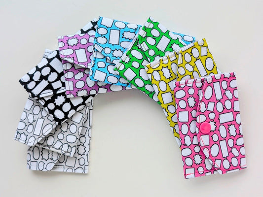 Colorful patterned fabric mini wallets arranged in a semi-circle on a light background
