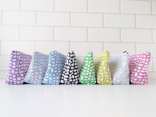 Set of colorful patterned pouches on a white surface with a tiled wall background
